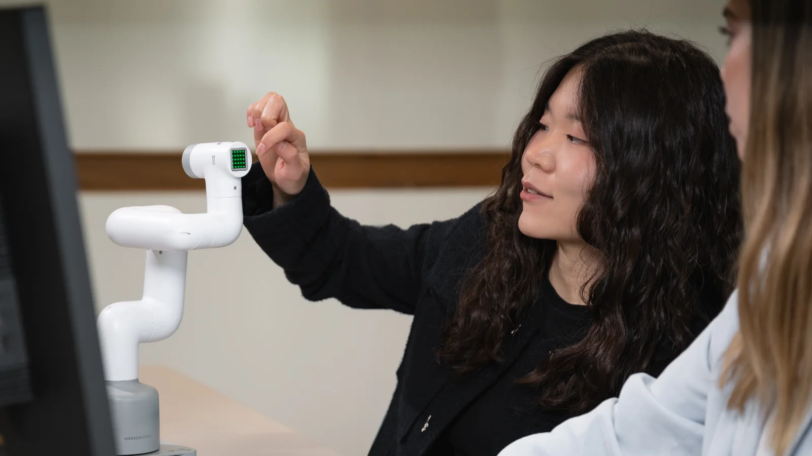 student working on robotic arm Young female engineer in training with robotic devices