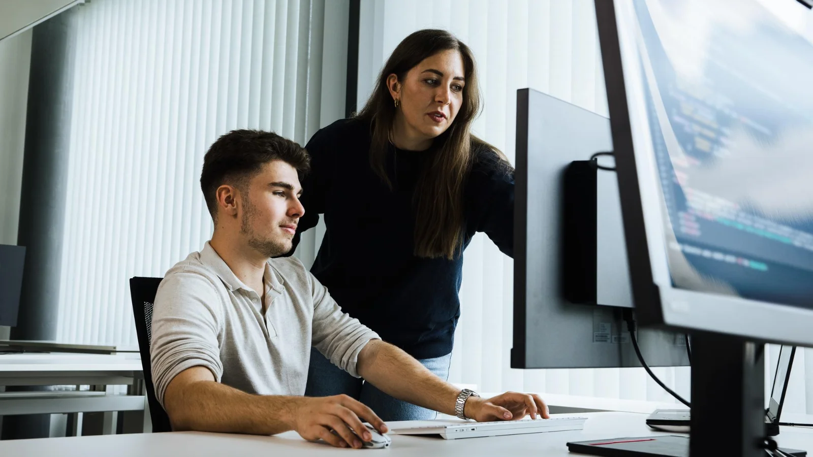 Develop certification expertise with hands-on learning and real-world application. Two professionals working together on a computer in a modern office environment, applying technical skills and collaborating on real-world development tasks.