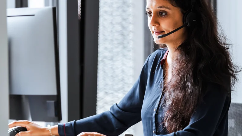 Contact us for further information A woman wearing a headset is sitting at a desk